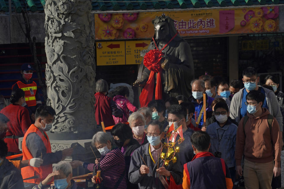 Worshippers wearing face masks to protect against the spread of the coronavirus, queue beside the statue of ox as they pray at the Wong Tai Sin Temple, in Hong Kong, Friday, Feb. 12, 2021 to celebrate the Lunar New Year which marks the Year of the Ox in the Chinese zodiac. (AP Photo/Kin Cheung)