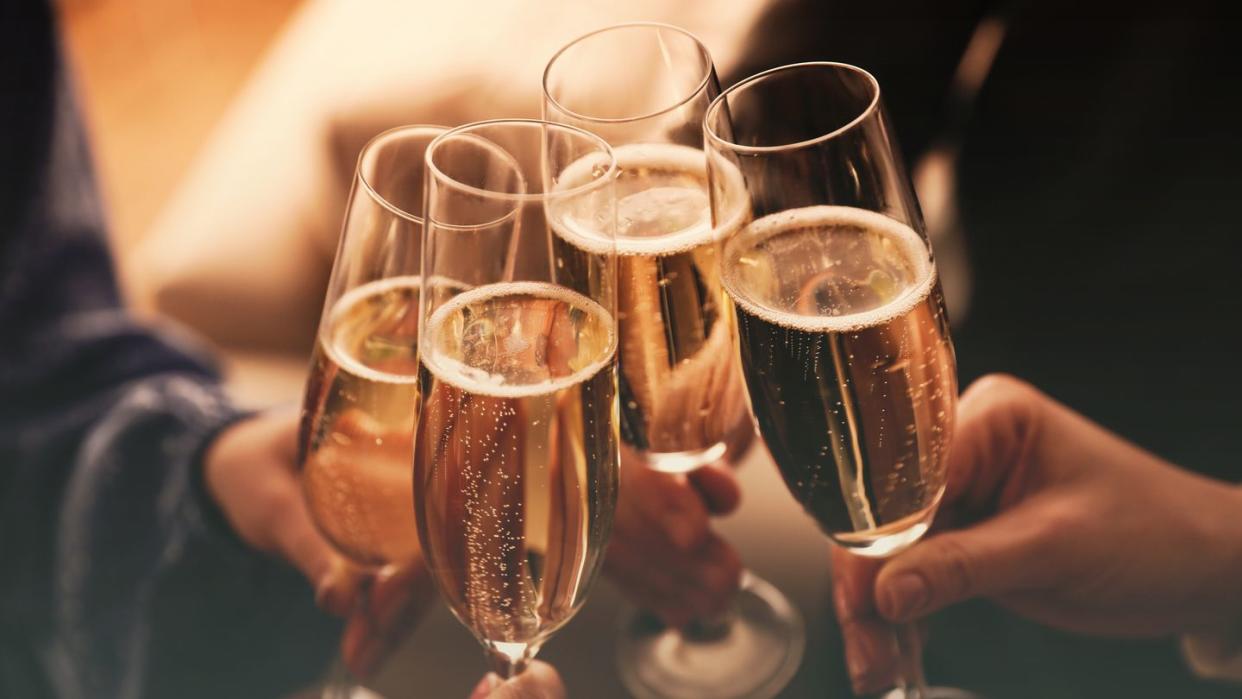 people clinking glasses with sparkling wine indoors , closeup