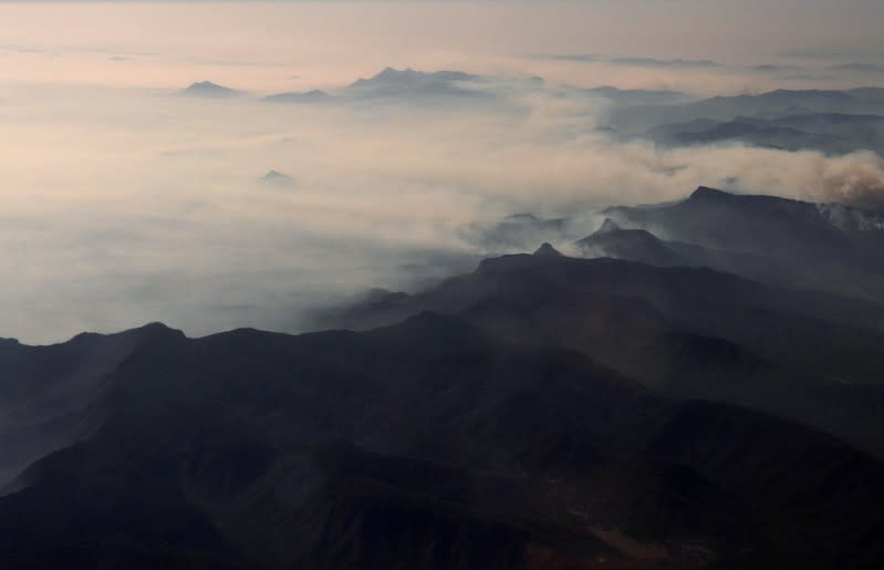 FILE PHOTO: Smoke from bushfires blanket mountain ranges as seen during a commercial flight over northern New South Wales