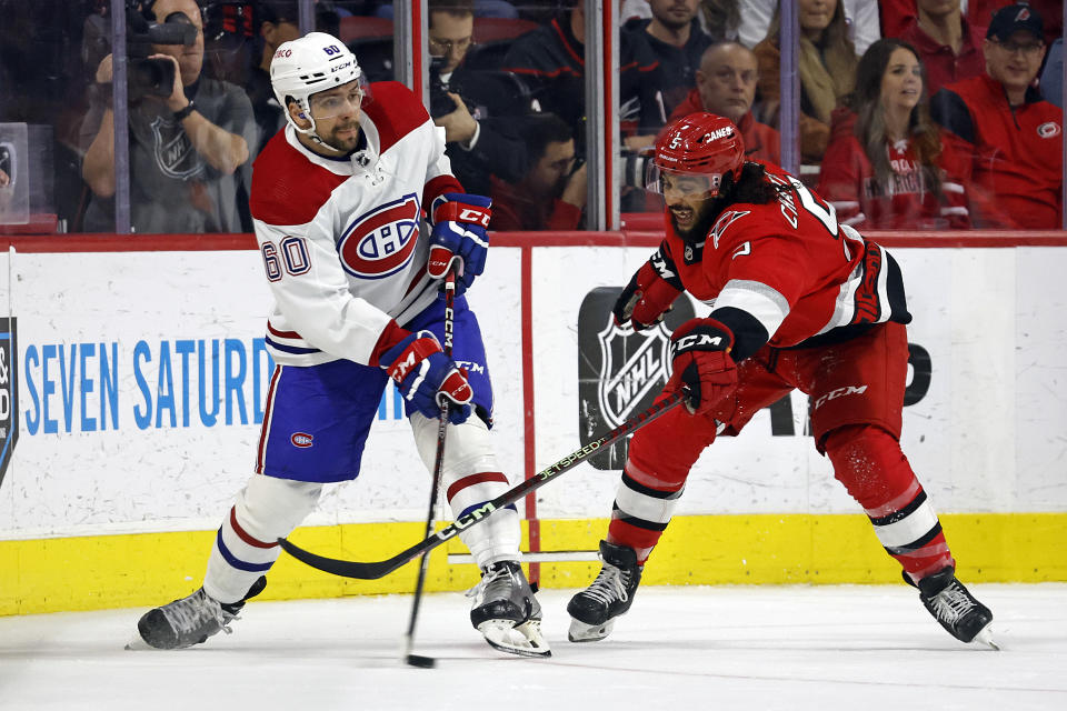 Montreal Canadiens' Alex Belzile (60) clears the puck around Carolina Hurricanes' Jalen Chatfield (5) during the second period of an NHL hockey game in Raleigh, N.C., Thursday, Feb. 16, 2023. (AP Photo/Karl B DeBlaker)