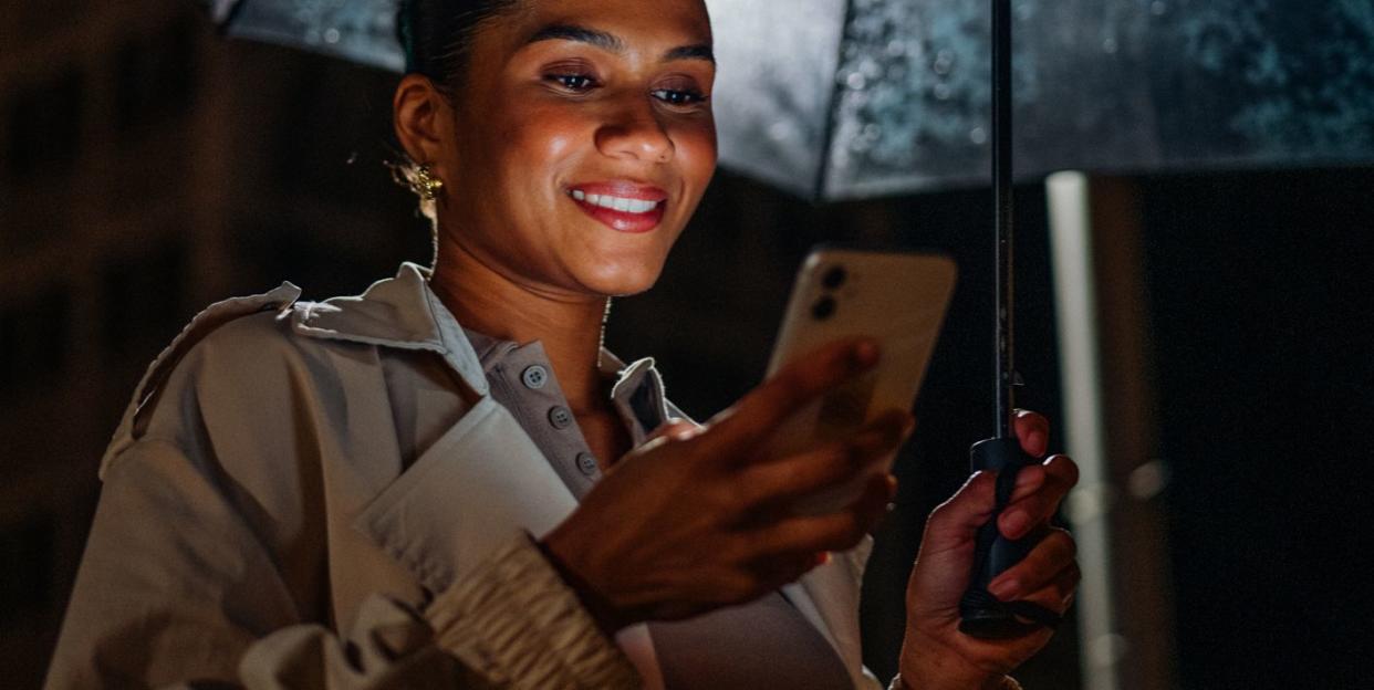 business woman with mobile phone, laptop, umbrella in the city at night in the rain part of a series with video