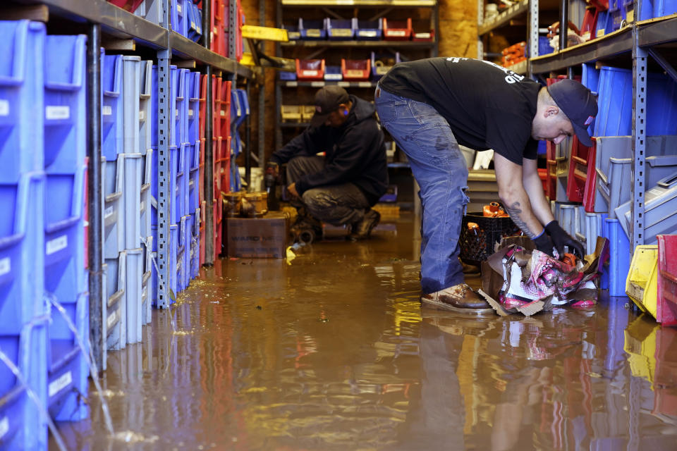 Louis Dearani, Jr., right, helps to clean up after his family business, United Automatic Fire Sprinkler, was flooded from the remnants of Hurricane Ida that hit the area in Woodland Park, N.J., Thursday, Sept. 2, 2021. (AP Photo/Seth Wenig)