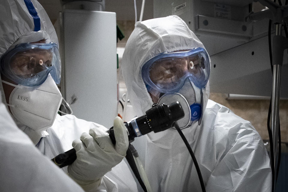 In this photo taken on Friday, May 15, 2020, Dr. Osman Osmanov, center, and Dr. Konstantin Glebov, center left, perform tracheal intubation of a coronavirus patient on artificial lung respiration at an intensive care unit of the Filatov City Clinical Hospital in Moscow, Russia. Moscow accounts for about half of all of Russia's coronavirus cases, a deluge that strains the city's hospitals and has forced Osmanov to to work every day for the past two months, sometimes for 24 hours in a row. (AP Photo/Pavel Golovkin)