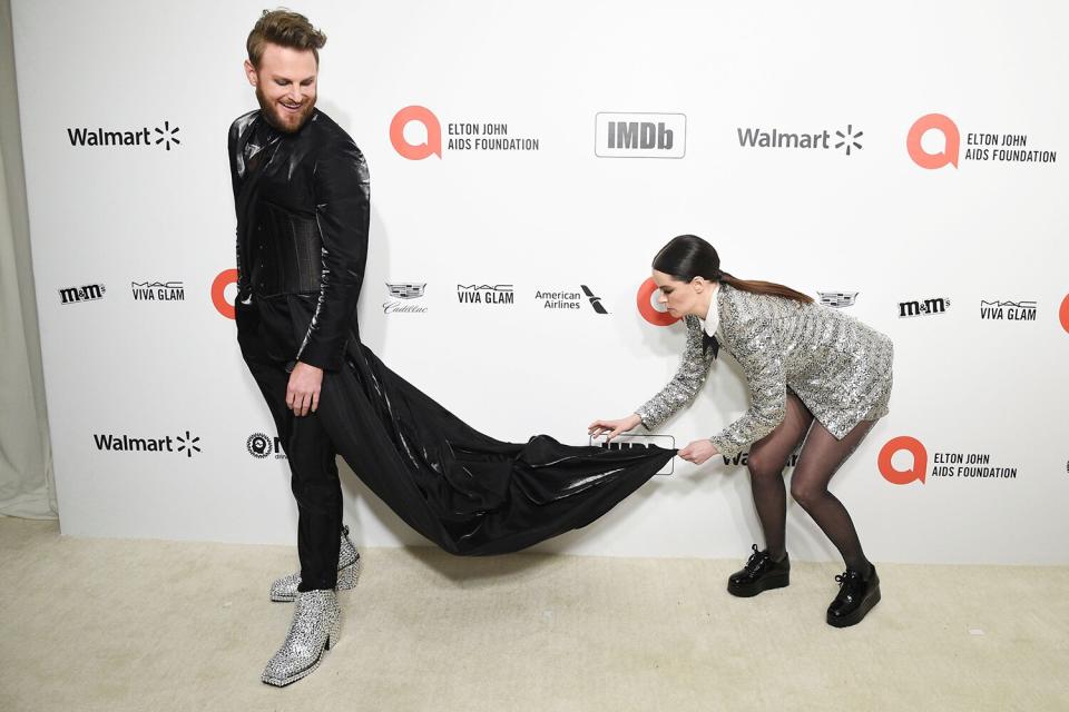 <em>Schitt's Creek</em>'s Emily Hampshire fixes Bobby Berk's train outside of the Elton John AIDS Foundation Oscar Viewing Party. 