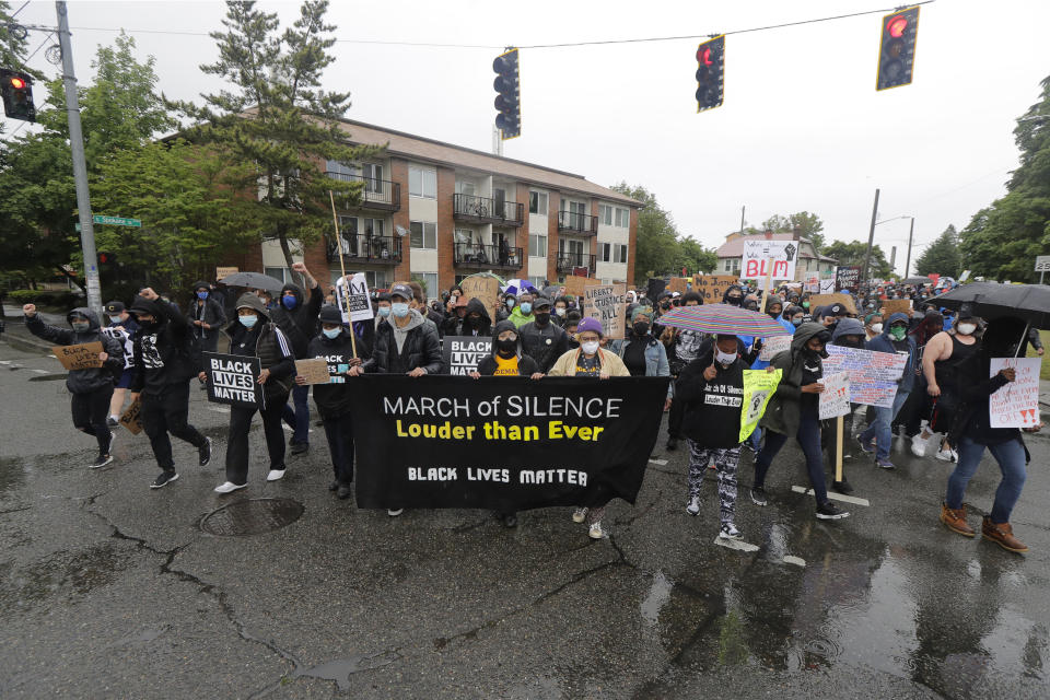 Protesters leaving a "March of Silence" against racial inequality and police brutality that was organized by Black Lives Matter Seattle-King County turn a corner near Jefferson Park, Friday, June 12, 2020, in Seattle. People marched for nearly two miles to support Black lives, oppose racism and to call for police reforms among other issues. (AP Photo/Ted S. Warren)