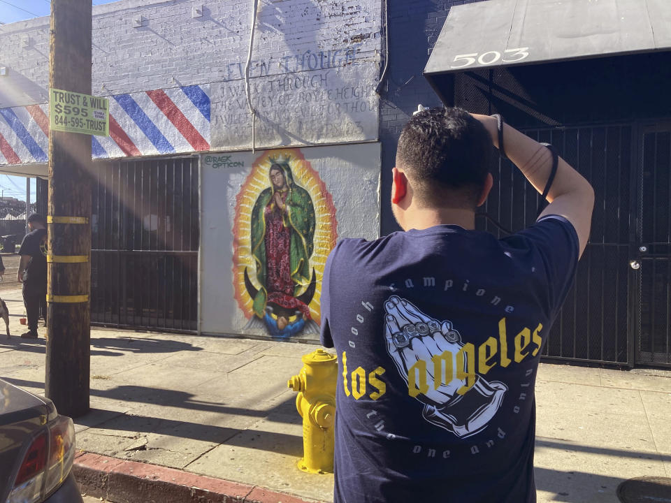 Oscar Rodriguez Zapata fotografía una imágen de la Guadalupana pintada en una pared en Los Ángeles, el sábado 21 de enero de 2021. (Alejandra Molina/Religion News Service vía AP)