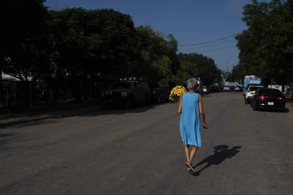 A woman walks toward Robb Elementary School to lay flowers for the victims killed in this week's school shooting in Uvalde, Texas Saturday, May 28, 2022. (AP Photo/Jae C. Hong)