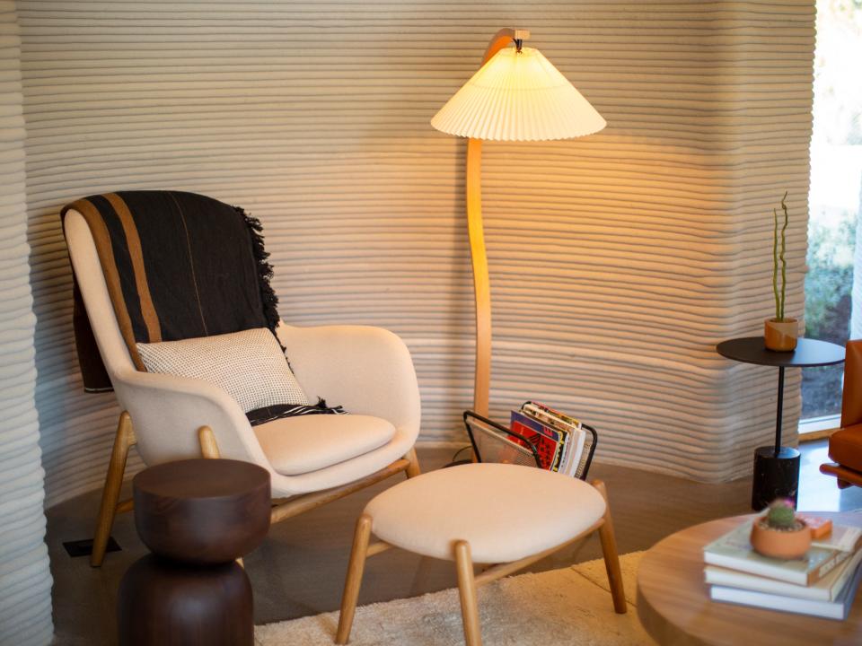 A lounge chair next to a light in the living room.