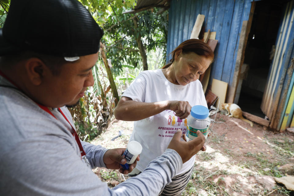 Lourdes Betancourt prepares a jar containing mosquito eggs to hang from a tree in her yard, in Tegucigalpa, Honduras, Wednesday, Aug. 23, 2023. The mosquitoes that hatch will carry bacteria called Wolbachia that interrupt the transmission of dengue. (AP Photo/Elmer Martinez)