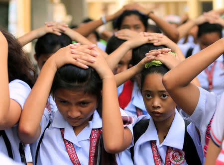 Students use their hands to cover their heads as they evacuate their school premises after an earthquake of magnitude 6.2 hit the northern island of Luzon and was felt in the Metro Manila, Philippines August 11, 2017, shaking buildings and forcing the evacuation of offices and schools. REUTERS/Romeo Ranoco