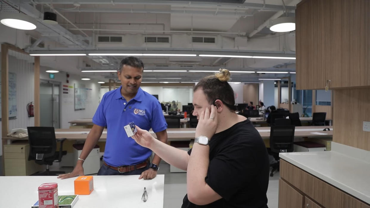  A man with a visual impairment using a wearable device to describe an object he is holding. 