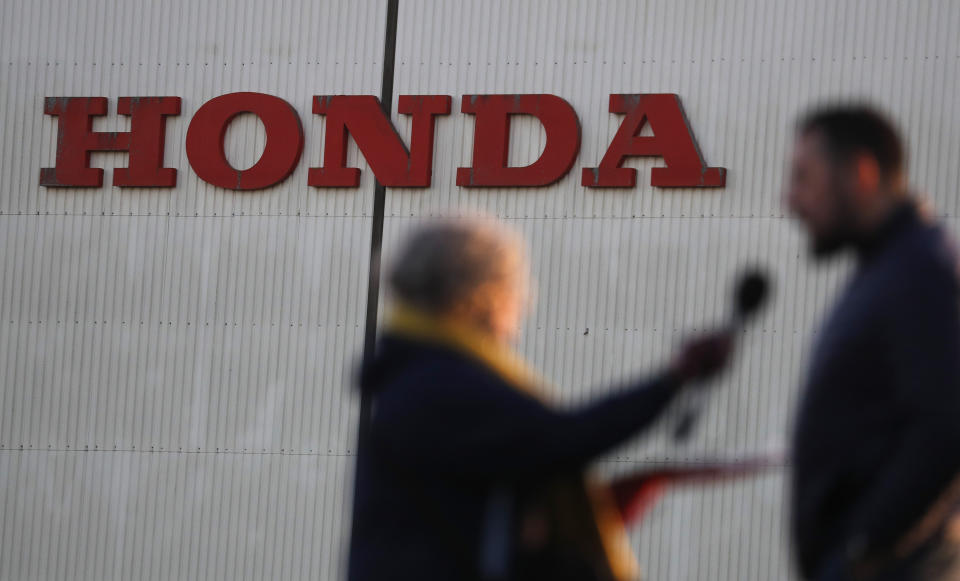 A journalist speaks to an employee at the entrance of the Honda car plant in Swindon, England, Tuesday, Feb. 19, 2019. The Japanese carmaker Honda announced Tuesday that its Swindon car plant in western England, will close in 2022, with the potential loss of some 3,500 jobs.(AP Photo/Frank Augstein)