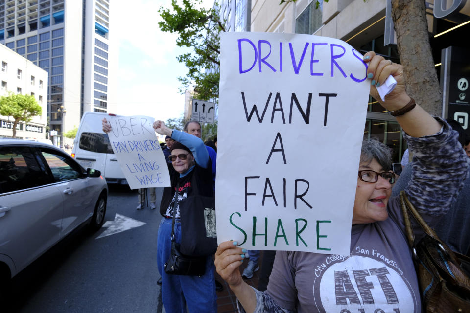 FILE - In this May 8, 2019, file photo Uber and Lyft drivers carry signs during a demonstration outside of Uber headquarters in San Francisco. A California law that makes it harder for companies to treat workers as independent contractors takes effect next week, forcing small businesses in and outside the state to rethink their staffing. (AP Photo/Eric Risberg, File)