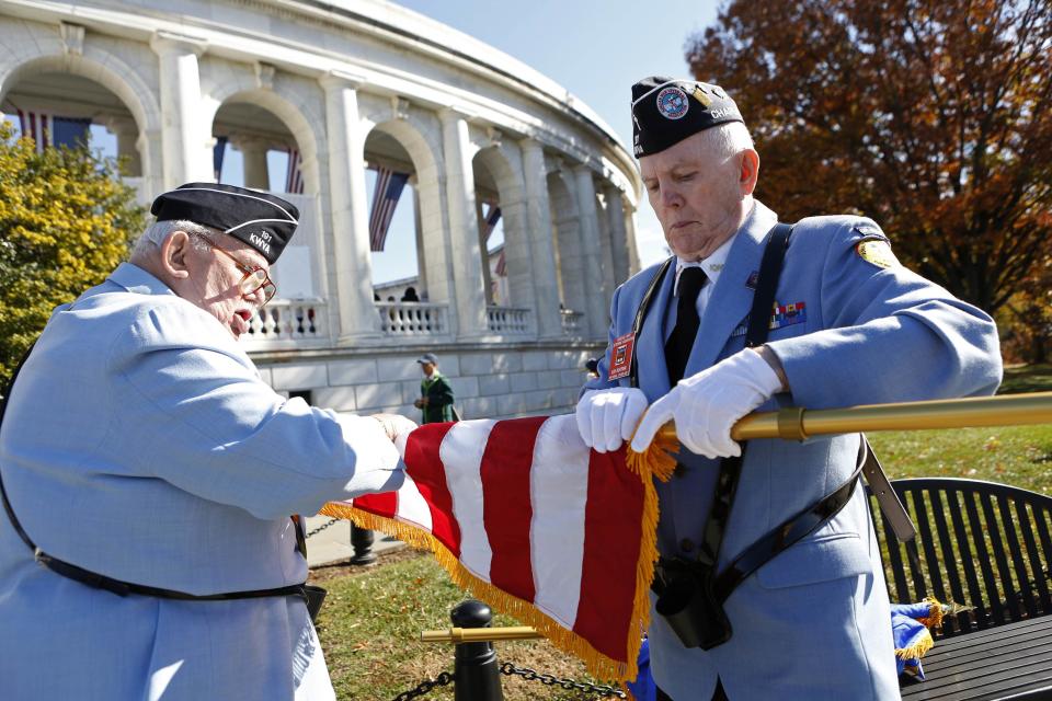 Members of a veterans' honor guard furl a flag after a ceremony at Arlington National Cemetery on Veterans Day in Washington