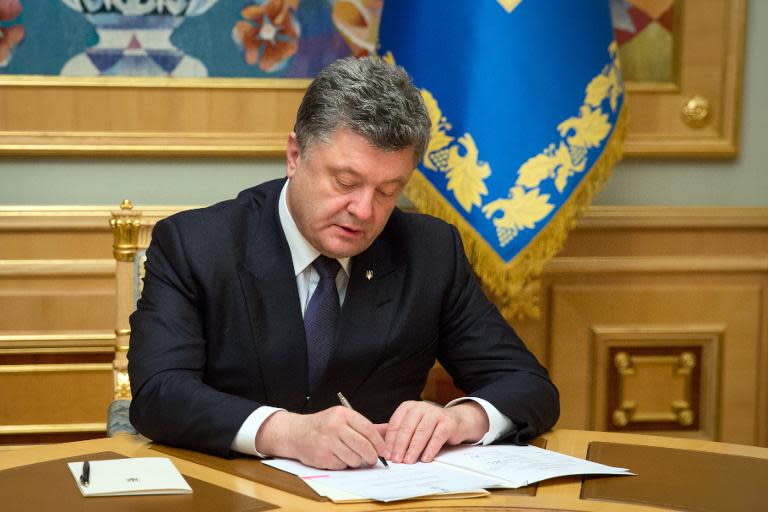 Ukrainian President Petro Poroshenko signs a resignation letter for Dnipropetrovsk Governor Igor Kolomoisky at his office in Kiev, on March 25, 2015
