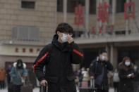 A man adjusts his face mask to help curb the spread of the coronavirus walks out from the Beijing railway station as passenger arrive in Beijing, Tuesday, Jan. 19, 2021. China is now dealing with coronavirus outbreaks across its frigid northeast, prompting additional lockdowns and travel bans. (AP Photo/Andy Wong)