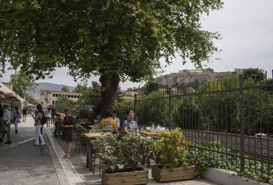 People sit on the terrace of a cafe, in Monastiraki district of Athens, with the Acropolis hill in the background, Monday, May 3, 2021. Cafes and restaurants have reopened in Greece for sit-down service for the first time in nearly six months, as the country began easing coronavirus-related restrictions with a view to opening to the vital tourism industry in the summer. (AP Photo/Petros Giannakouris)