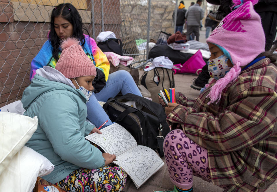 Two young migrants from Venezuela share a coloring book while waiting for help in downtown El Paso, Texas, Sunday, Dec. 18, 2022. Texas border cities were preparing Sunday for a surge of as many as 5,000 new migrants a day across the U.S.-Mexico border as pandemic-era immigration restrictions expire this week, setting in motion plans for providing emergency housing, food and other essentials. (AP Photo/Andres Leighton)