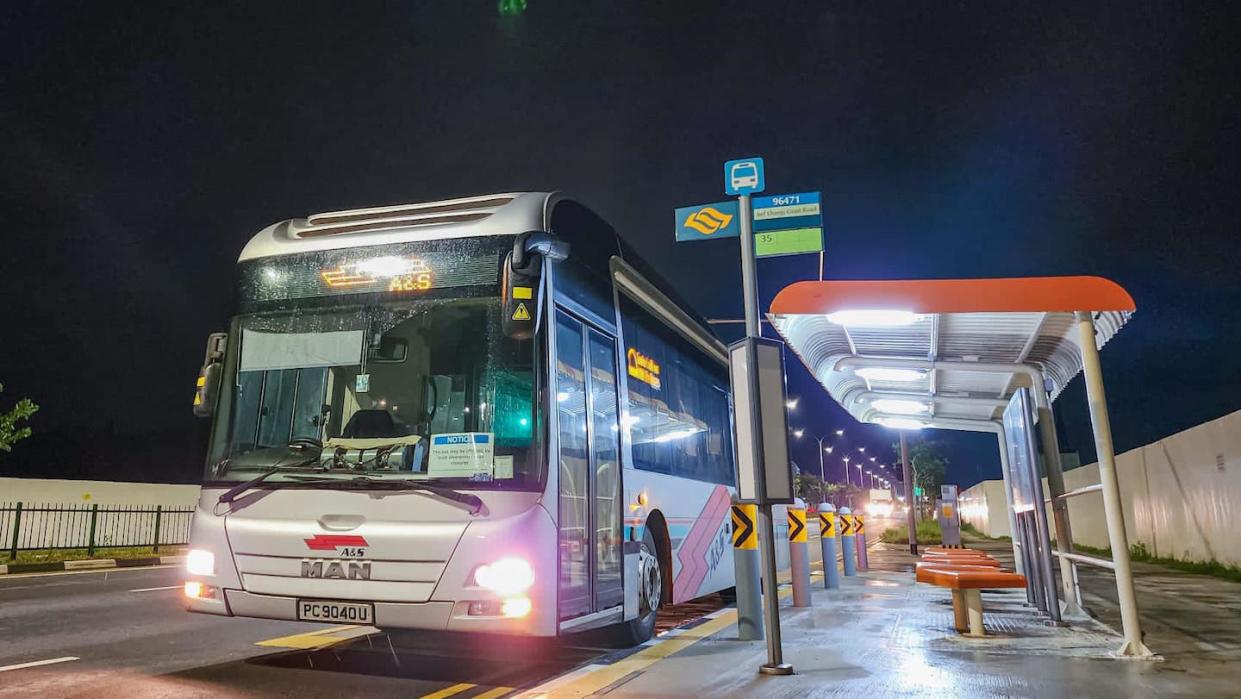 A&S Transit bus parked beside an orange bus stop in Singapore at night