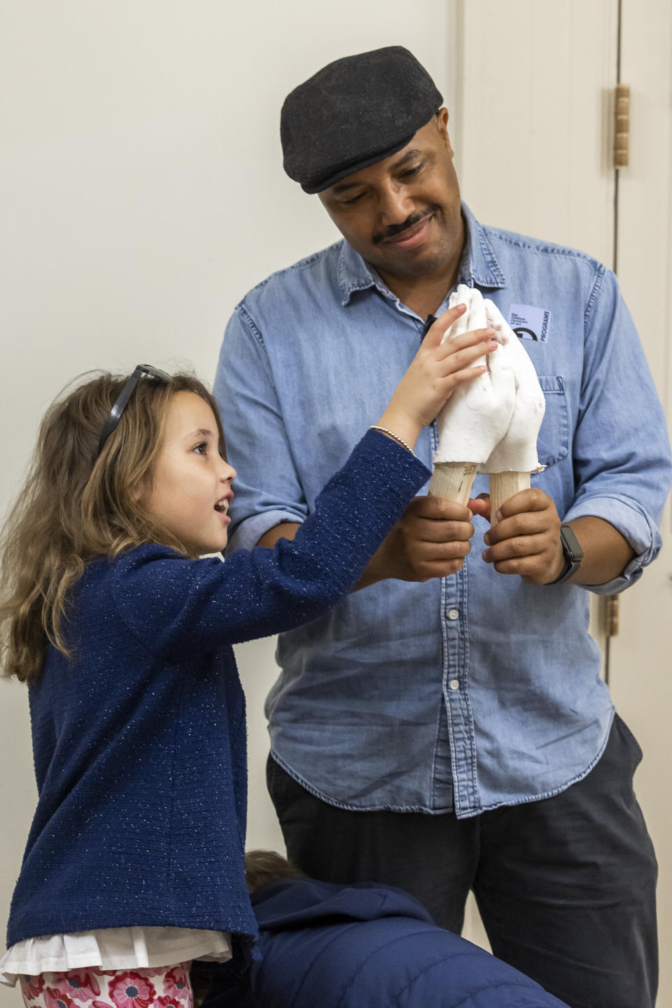 Christopher Frisby shows his daughter, Mary, his molded hands in Charleston, S.C., Saturday, Feb. 18, 2023. Artist Stephen Hayes will use the mold to make a memorial for 36 enslaved people whose bodies were unearthed in Charleston in 2013 during a construction project for the Gaillard Center. (AP Photo/Mic Smith)