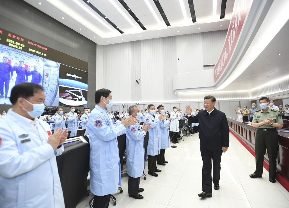 In this photo released by China's Xinhua News Agency, Chinese President Xi Jinping greets workers after having a video conversation with the three astronauts aboard China's space station core module Tianhe at the Beijing Aerospace Control Center in Beijing, Wednesday, June 23, 2021. (Yan Yan/Xinhua via AP)