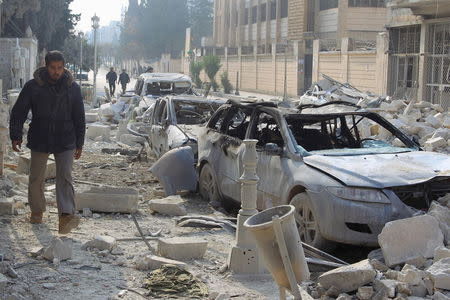 A man walks past damaged cars at a site hit by what activists said were airstrikes carried out by the Russian air force in Idlib city, Syria December 20, 2015. REUTERS/Ammar Abdullah