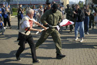 A police officer tries to take away an old Belarusian national flag from Nina Bahinskaya's hands during an opposition rally to protest the official presidential election results in Minsk, Belarus, Saturday, Sept. 26, 2020. Hundreds of thousands of Belarusians have been protesting daily since the Aug. 9 presidential election. (AP Photo/TUT.by)