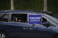 People wave a sign supporting President Donald Trump from the window of a passing car as they pass an early voting location located across the street from Trump International Golf Club in West Palm Beach, Fla., Friday, Oct. 30, 2020.(AP Photo/Rebecca Blackwell)