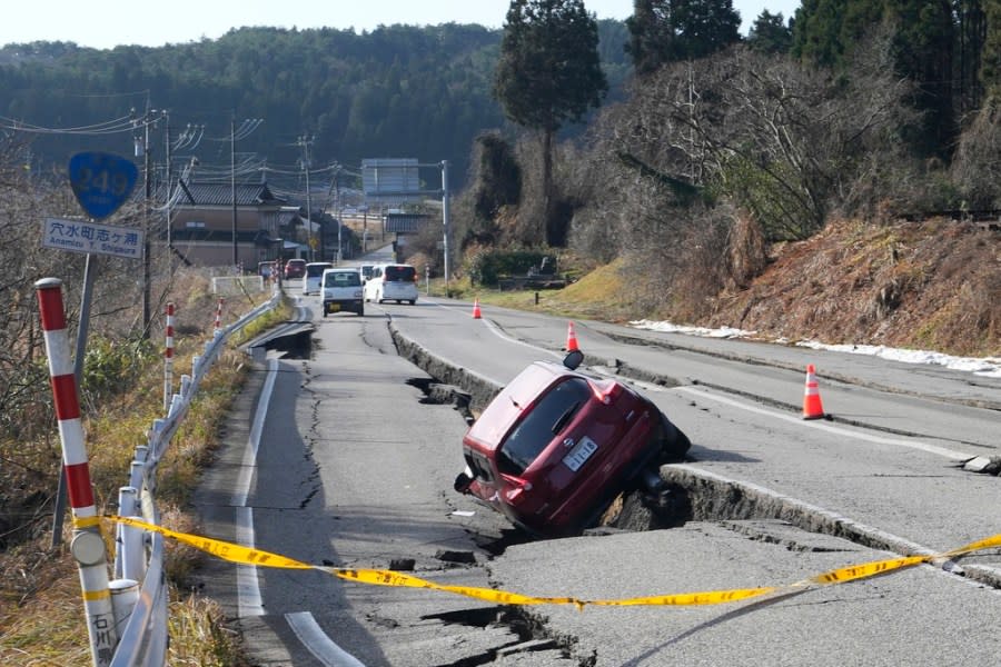 A car is trapped at a partially collapsed road caused by a powerful earthquake near Anamizu Town, Ishikawa Prefecture Tuesday, Jan. 2, 2024. A series of powerful earthquakes hit western Japan, damaging buildings, vehicles and boats, with officials warning people in some areas on Tuesday to stay away from their homes because of a risk of more strong quakes. (AP Photo/Hiro Komae)