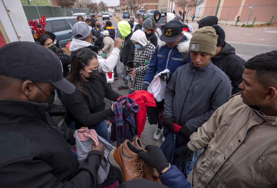 Migrants look through donated clothing on a street in downtown El Paso, Texas, Sunday, Dec. 18, 2022. Texas border cities were preparing Sunday for a surge of as many as 5,000 new migrants a day across the U.S.-Mexico border as pandemic-era immigration restrictions expire this week, setting in motion plans for providing emergency housing, food and other essentials. (AP Photo/Andres Leighton)