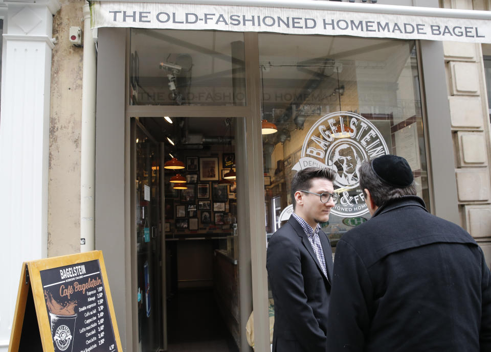 Bagel shop owner Alexandre Jankowiak, center, which shop was sprayed with the German word "Juden" on its front window last week, talks with a member of the Jewish community in Paris, Tuesday, Feb.12, 2019. According to French authorities, the total of registered anti-Semitic acts rose to 541 in 2018 from 311 in 2017, a rise of 74 percent. (AP Photo/Christophe Ena)