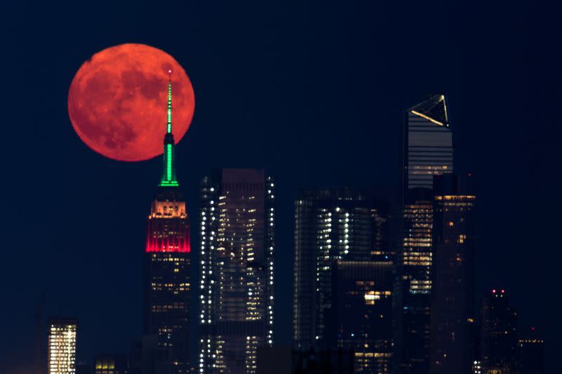 The full moon rises behind the Empire State Building in New York City