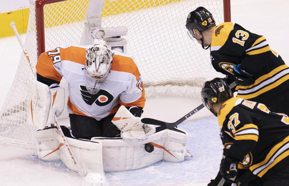 Philadelphia Flyers goaltender Carter Hart (79) makes a save as Boston Bruins centers Charlie Coyle (13) and Patrice Bergeron (37) close in during third-period NHL hockey playoff action in Toronto, Sunday, Aug. 2, 2020. (Frank Gunn/The Canadian Press via AP)