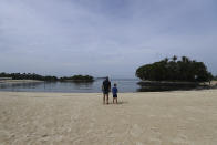 Tourists view the oil spill along Sentosa's Tanjong Beach area in Singapore, Sunday, June 16, 2024. An oil spill caused by a dredger boat hitting a stationary cargo tanker has blackened part of Singapore’s southern coastline, including the popular resort island of Sentosa, and sparked concerns it may threaten marine wildlife. (AP Photo/Suhaimi Abdullah)