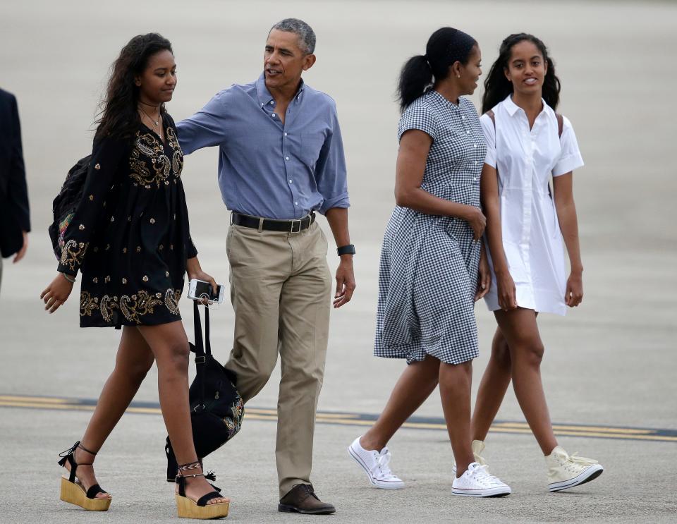 President Barack Obama, center, and first lady Michelle Obama, second from right, walk with their daughters, Sasha, left, and Malia on the tarmac to board Air Force One at the Cape Cod Coast Guard Station, in Bourne, Mass., on Aug. 21, 2016. President Obama and the first family are returning to Washington D.C. following their vacation on the island of Martha's Vineyard, in Massachusetts. 