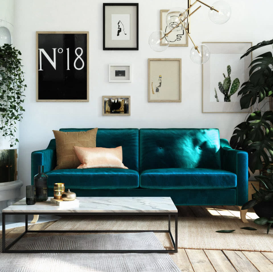 Contemporary living room with a velvet sofa, various framed wall art, and indoor plants