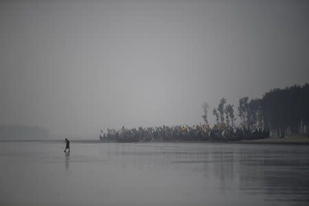A Rohingya refugee walks past a fishing colony on Shamlapur beach in Cox's Bazaar, Bangladesh, March 21, 2018. REUTERS/Clodagh Kilcoyne