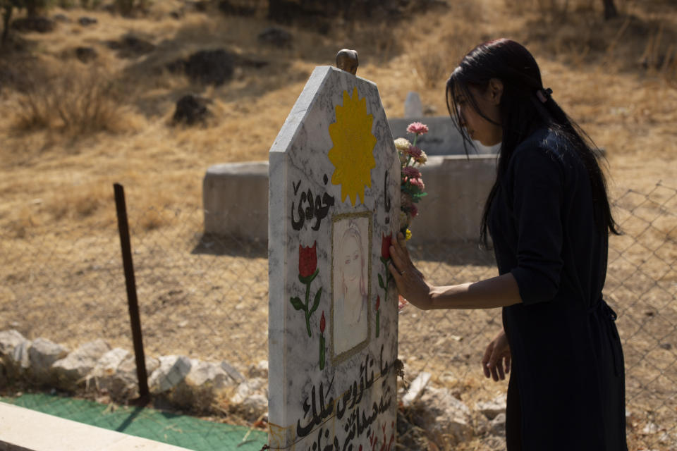 In this Sept. 13, 2019 photo, Layla Taloo visits the grave of a Yazidi woman who took her own life after she was captured by Islamic State militants in Mosul, buried on a hill overlooking the Lalish shrine in northern Iraq. Some 3,500 slaves have been freed from IS' clutches in recent years, most of them ransomed by their families. But more than 2,900 Yazidis remain unaccounted for, including some 1,300 women and children, according to the Yazidi abductees office in Iraq's Kurdish autonomous region. (AP Photo/Maya Alleruzzo)