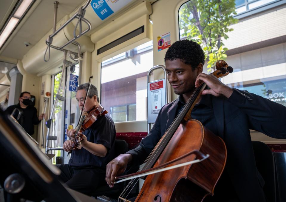 Two Detroit Symphony Orchestra members Mike Chen, 51, left, and Cole Randolph, 26, play the viola and cello inside a QLINE streetcar in Detroit on Aug. 17, 2022.