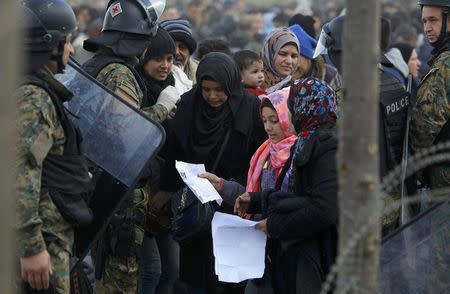 Macedonian police check the papers of migrants, as they wait to cross the border from Greece to Gevgelija, Macedonia November 22, 2015. REUTERS/Ognen Teofilovski