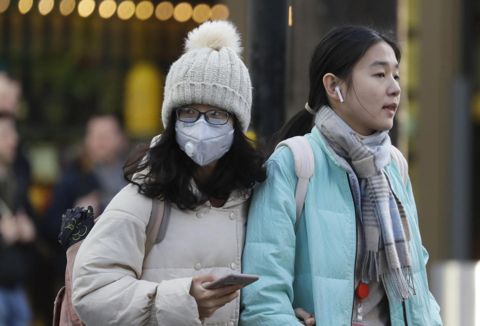 A woman wears a mask as she walks near China Town in London, Friday, Feb. 7, 2020. The director-general of the World Health Organization says a drop in the number of new coronavirus cases for two days is “good news” but cautions against reading too much into that. China reported 31,161 cases in mainland China in its update Friday. (AP Photo/Kirsty Wigglesworth)