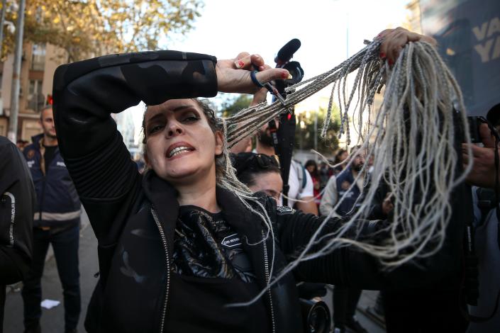 An Iranian woman cuts her hair during a demonstration outside the Iranian consulate in Istanbul, Saturday, Oct. 22, 2022. Demonstrators protested against the death of Mahsa Amini, a 22-year-old woman who had been detained by Iran's morality police in the capital of Tehran for allegedly not adhering to Iran's strict Islamic dress code.