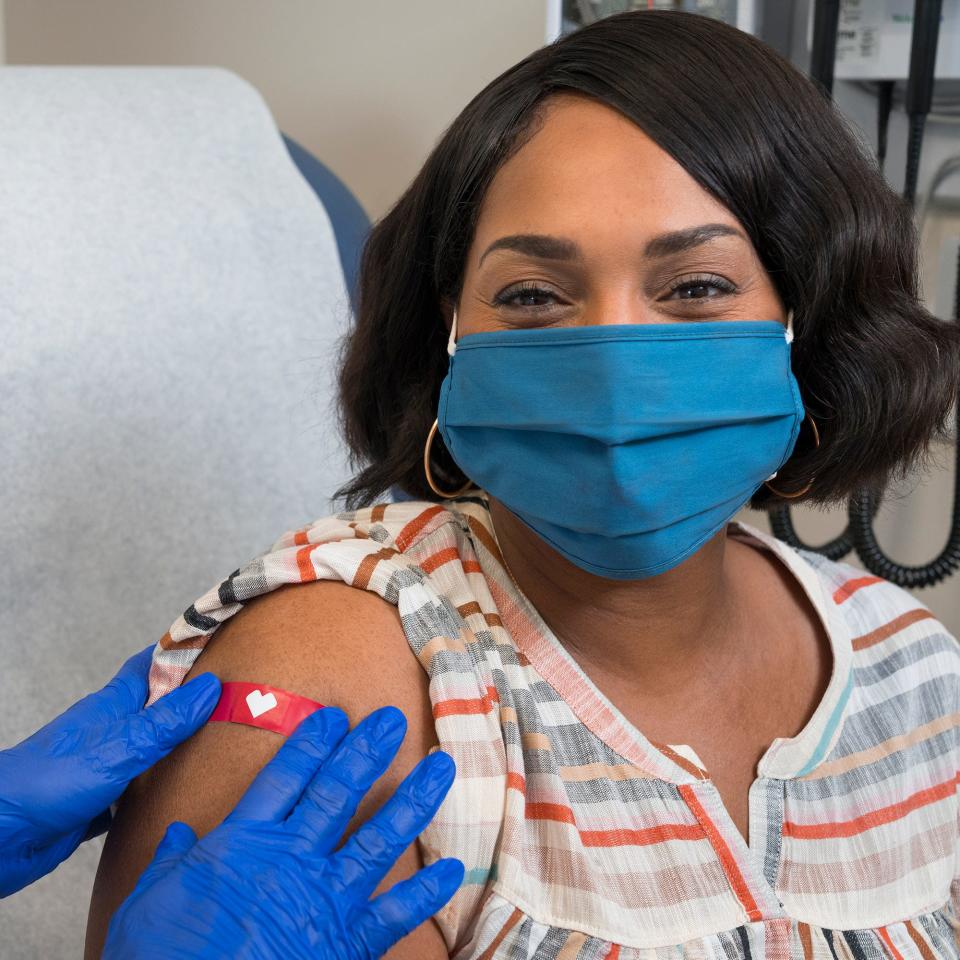 In this undated file photo, a woman smiles after having received a dose of the COVID-19 vaccine, as a CVS Pharmacy employee places a bandage on her right upper arm.