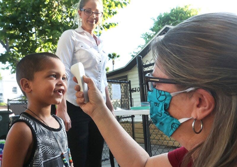 Kamryn Garves, 4, curiously looks up at the no-contact infrared thermometer as teacher Denise Mueller checks his temperature May 13. It's a daily ritual during the coronavirus pandemic before his grandmother Andrea McMillian can drop him off at Imagination Station Montessori in Daytona Beach, Fla.