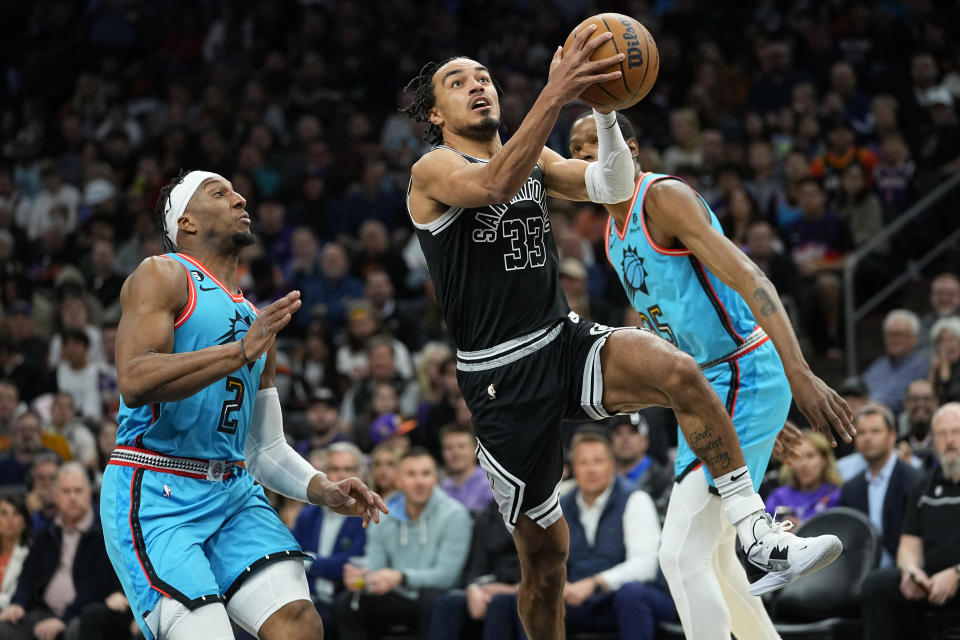 San Antonio Spurs guard Tre Jones (33) drives as Phoenix Suns forward Josh Okogie (2) looks on during the first half of an NBA basketball game, Tuesday, April 4, 2023, in Phoenix. (AP Photo/Matt York)