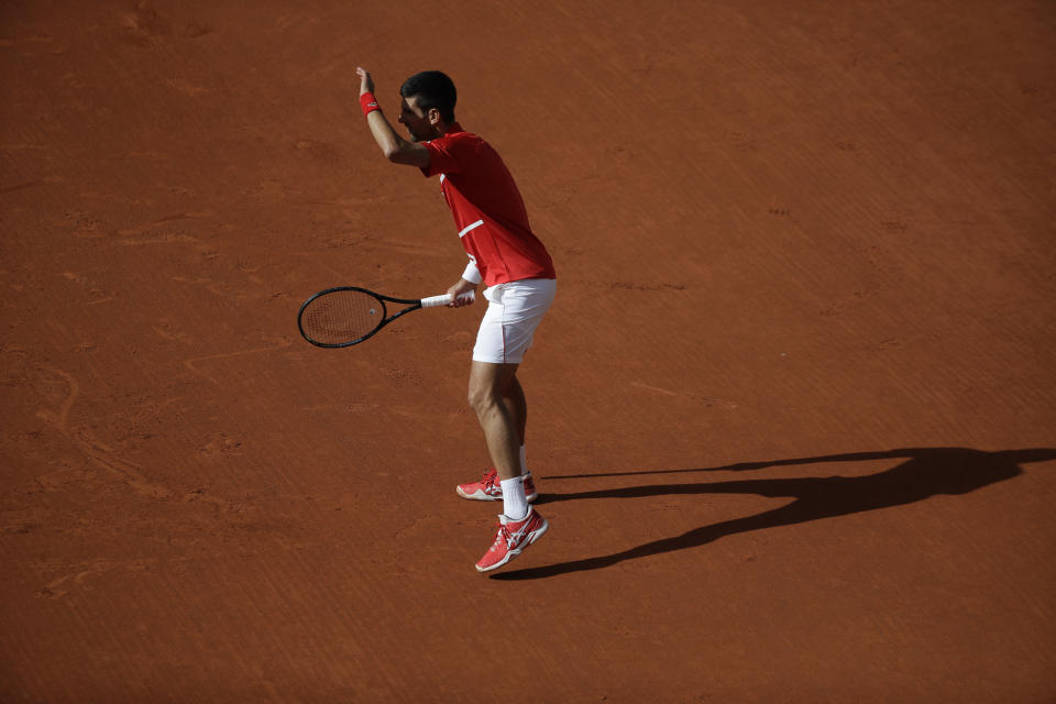 Serbia's Novak Djokovic shields his eyes from the sun as he watches Lithuania's Ricardas Berankis' serve in the second round match of the French Open tennis tournament at the Roland Garros stadium in Paris, France, Thursday, Oct. 1, 2020. (AP Photo/Alessandra Tarantino)