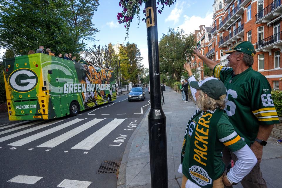 Waukesha couple Dennise and Don Lavrenz wave to the Green Bay Packers-themed double-decker bus carrying fans at the Abbey Road crosswalk made famous by the Beatles.