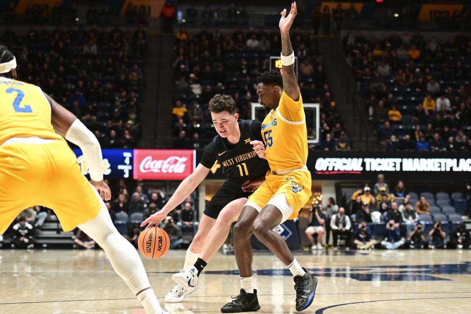 West Virginia forward Quinn Slazinski (11) protects the ball from Pittsburgh forward Zack Austin (55) during the first half of an NCAA college basketball game, Wednesday, Dec. 6, 2023, in Morgantown, W.V. (William Wotring/The Dominion-Post via AP)