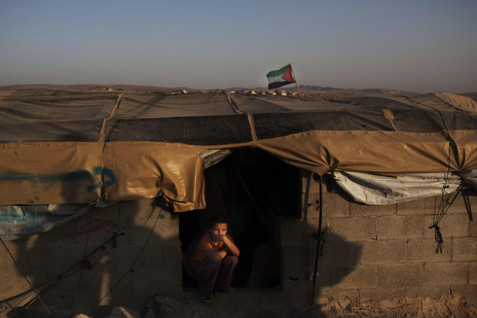 In this Friday, June 15, 2012 photo, a Palestinian child sits at the entrance of a house in the West Bank town of Susiya. Palestinian herders in this hamlet have clung to arid acres spread over several West Bank hills for decades, even as Israel forced them to live off the grid while providing water and electricity to nearby Jewish settlements and unauthorized outposts. But the end seems near for Susiya's 200 residents: Citing zoning violations, Israel is threatening to demolish the village, including German-funded solar panels. (AP Photo/Bernat Armangue)