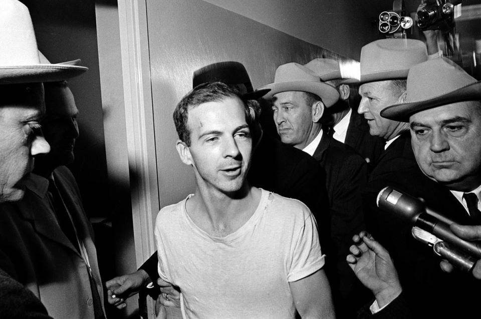 Surrounded by detectives, Lee Harvey Oswald talks to the media as he is led down a corridor of the Dallas police station (AP)